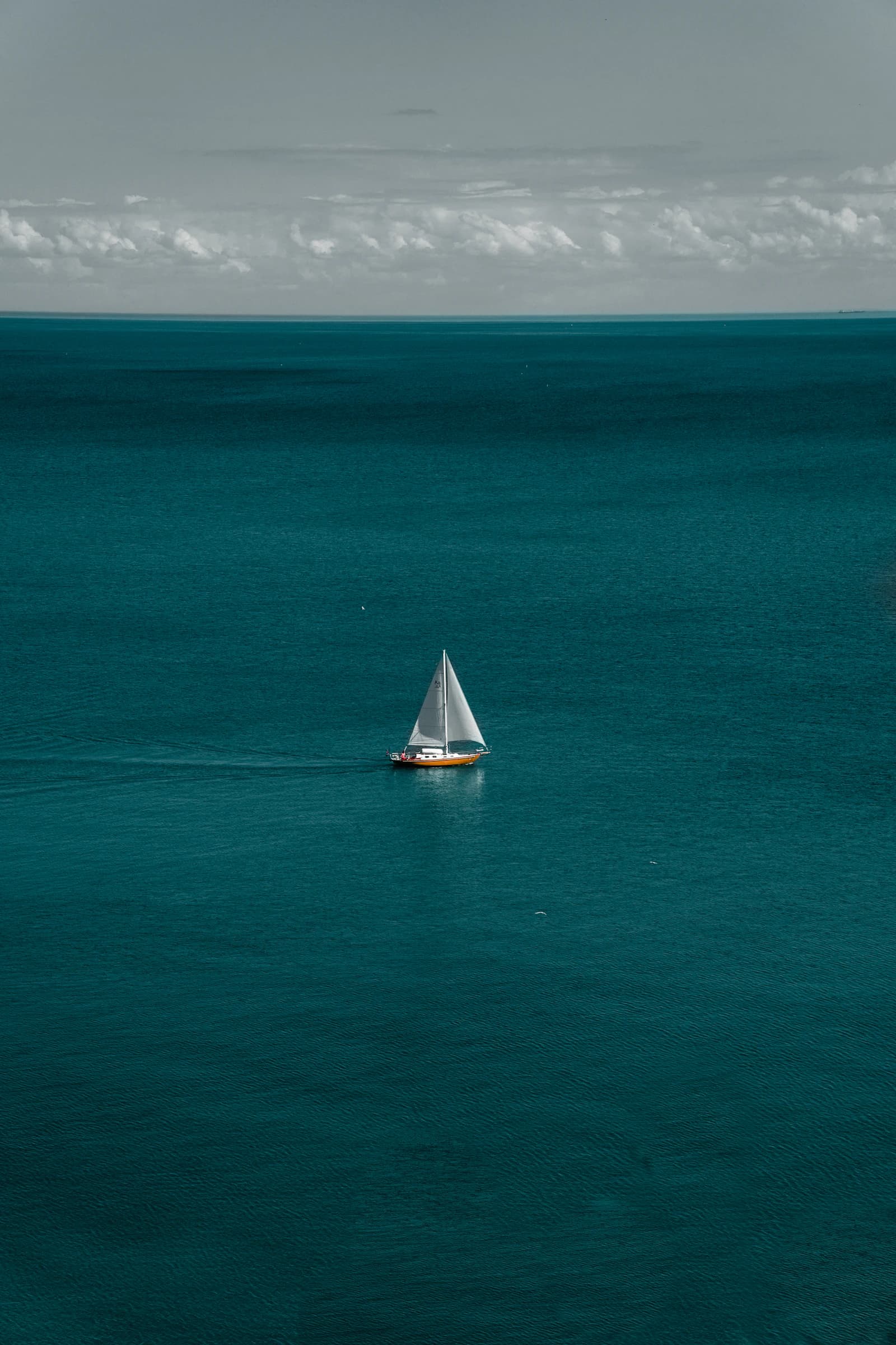 Velero solitario sobre agua turquesa