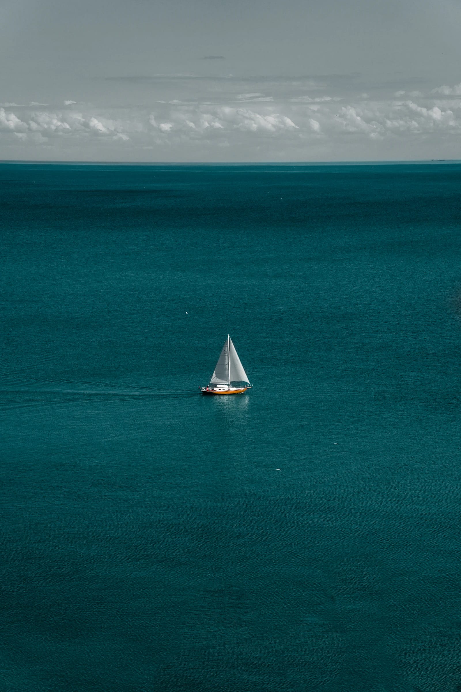 Velero solitario sobre agua turquesa