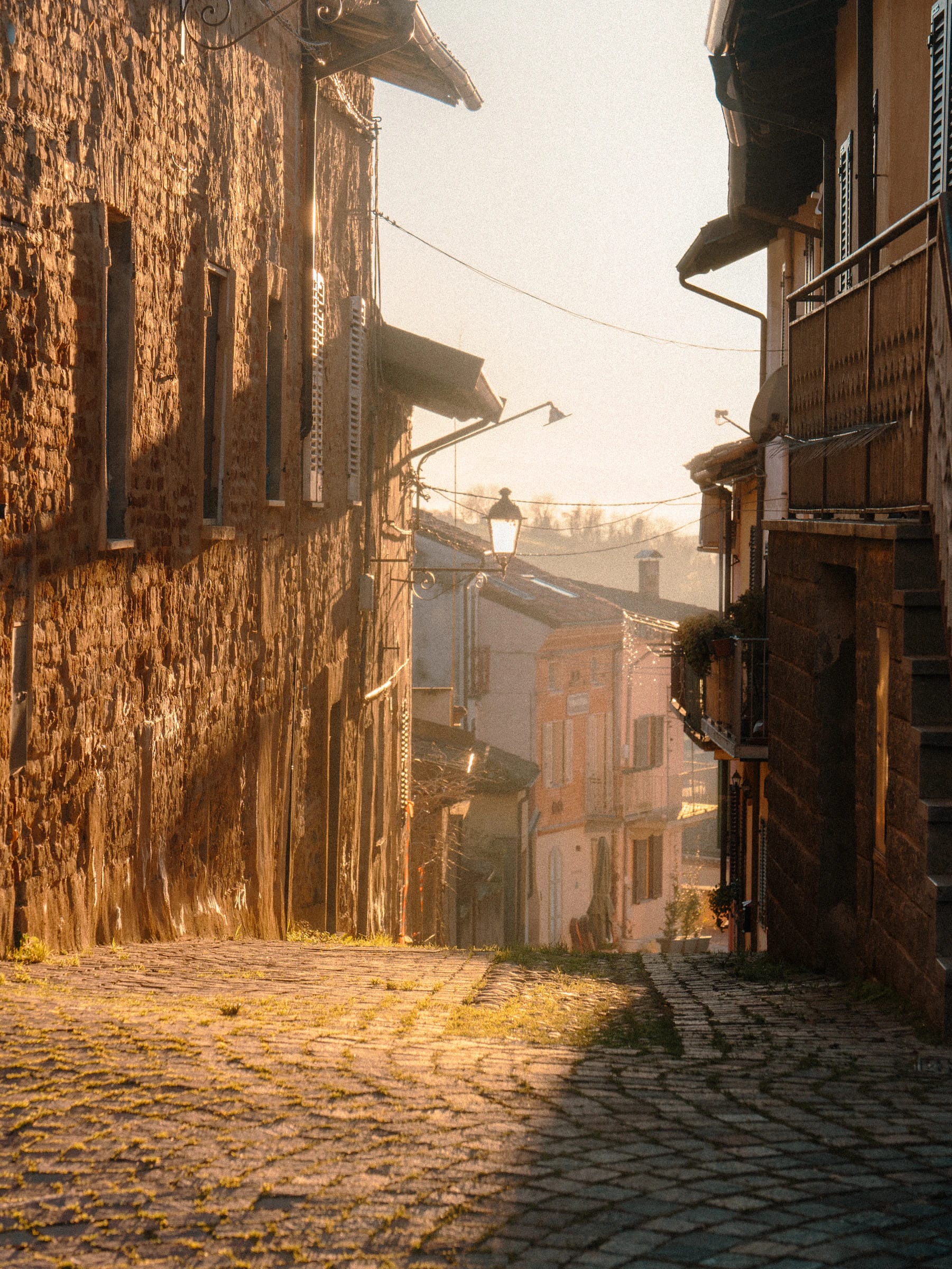 Calle empedrada vacía al amanecer, con luz dorada